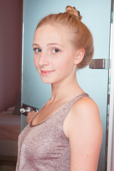Fair skinned teen wears her hair up while getting wet during a shower